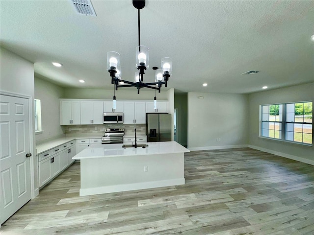 8051 N Pinkinz Way, Citrus Springs, FL 34433 - kitchen featuring stainless steel appliances, light wood-style flooring, a kitchen island with sink, a chandelier, and a textured ceiling