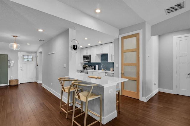 1322 N Bumby Ave, Orlando, FL 32803 - kitchen featuring stainless steel appliances, a breakfast bar, light countertops, white cabinets, and dark wood-style flooring