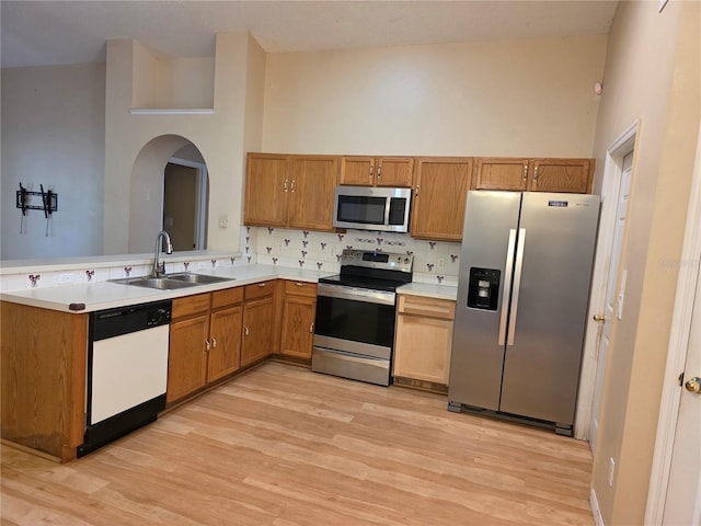 1797 Tillstream Dr, Orlando, FL 32818 - kitchen with stainless steel appliances, decorative backsplash, light wood-style floors, arched walkways, and light countertops