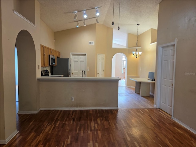 1797 Tillstream Dr, Orlando, FL 32818 - kitchen featuring arched walkways, appliances with stainless steel finishes, dark wood finished floors, rail lighting, and a textured ceiling