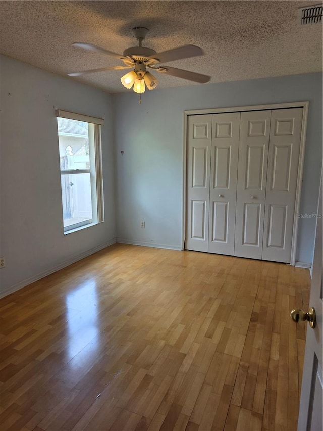 1797 Tillstream Dr, Orlando, FL 32818 - unfurnished bedroom featuring light wood finished floors, a textured ceiling, a closet, and ceiling fan