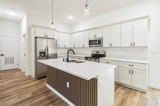 10599 N Umber Ter, Citrus Springs, FL 34434 - kitchen featuring appliances with stainless steel finishes, light wood-type flooring, hanging light fixtures, a kitchen island with sink, and light countertops