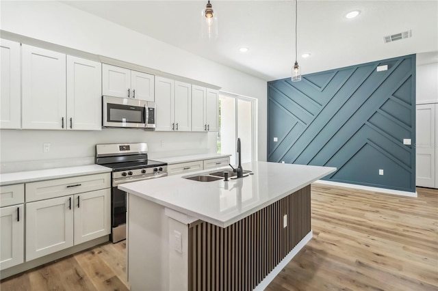 10599 N Umber Ter, Citrus Springs, FL 34434 - kitchen featuring stainless steel appliances, light wood-style floors, hanging light fixtures, light countertops, and a kitchen island with sink