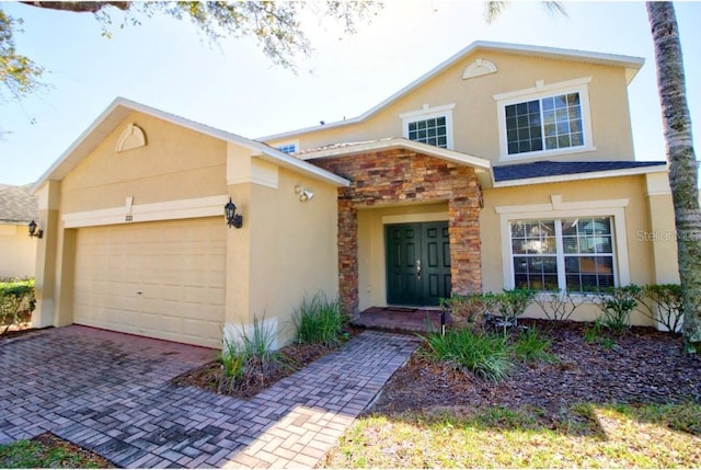 331 Bridgewater Dr, Davenport, FL 33897 - view of front of house featuring stone siding, stucco siding, a garage, and decorative driveway