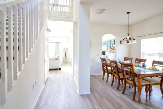 331 Bridgewater Dr, Davenport, FL 33897 - dining room with a chandelier, light wood-type flooring, arched walkways, and stairway