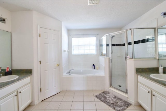 331 Bridgewater Dr, Davenport, FL 33897 - full bathroom featuring two vanities, a stall shower, a bath, tile patterned floors, and a textured ceiling