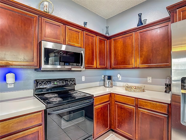 2530 The Oaks Blvd, Kissimmee, FL 34746 - kitchen with stainless steel appliances, light countertops, light tile patterned floors, a textured ceiling, and reddish brown cabinets