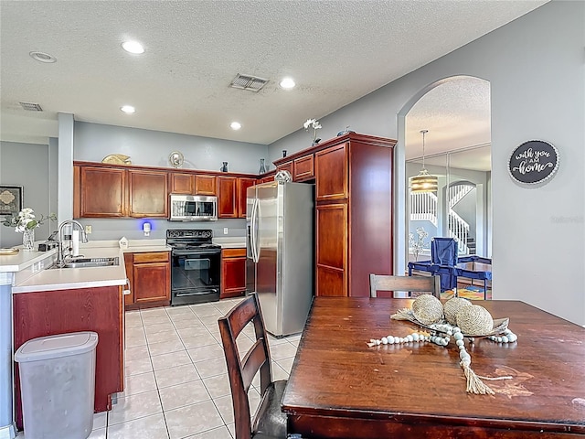 2530 The Oaks Blvd, Kissimmee, FL 34746 - kitchen with stainless steel appliances, arched walkways, a textured ceiling, light tile patterned floors, and light countertops