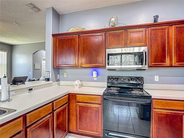 2530 The Oaks Blvd, Kissimmee, FL 34746 - kitchen featuring black / electric stove, stainless steel microwave, a textured ceiling, arched walkways, and light countertops