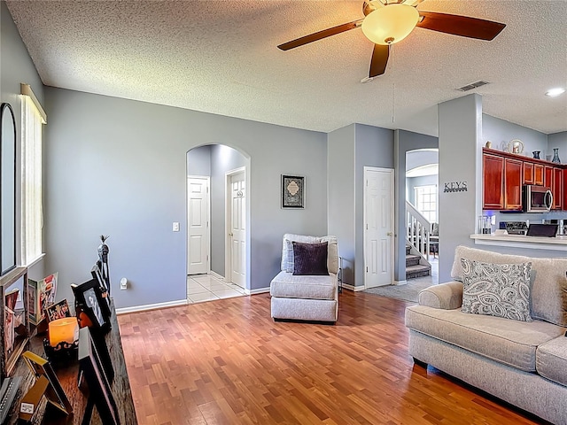 2530 The Oaks Blvd, Kissimmee, FL 34746 - living room featuring arched walkways, ceiling fan, light wood-style flooring, a textured ceiling, and stairway