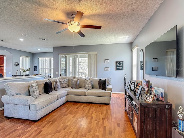 2530 The Oaks Blvd, Kissimmee, FL 34746 - living area featuring a textured ceiling, light wood finished floors, ceiling fan, and arched walkways