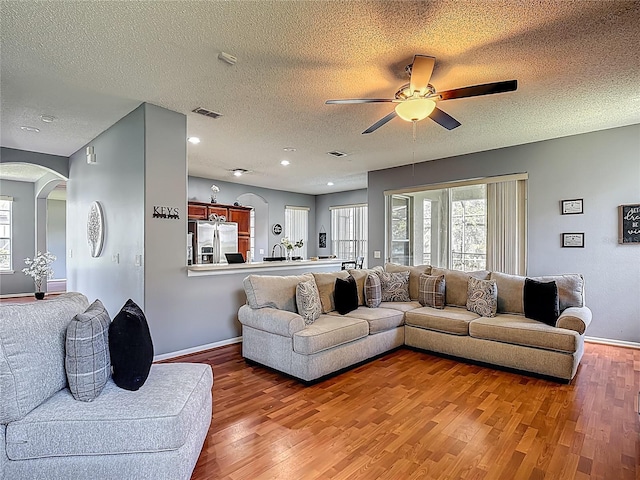 2530 The Oaks Blvd, Kissimmee, FL 34746 - living room with arched walkways, wood finished floors, ceiling fan, healthy amount of natural light, and a textured ceiling