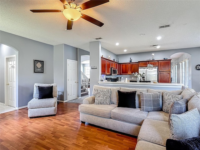 2530 The Oaks Blvd, Kissimmee, FL 34746 - living area featuring arched walkways, light wood-style floors, a textured ceiling, a ceiling fan, and stairway