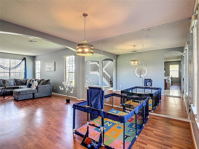 2530 The Oaks Blvd, Kissimmee, FL 34746 - dining space featuring arched walkways, a textured ceiling, wood finished floors, and plenty of natural light