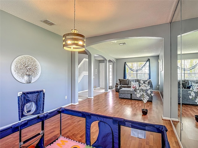 2530 The Oaks Blvd, Kissimmee, FL 34746 - dining room featuring a textured ceiling, wood finished floors, arched walkways, healthy amount of natural light, and stairs