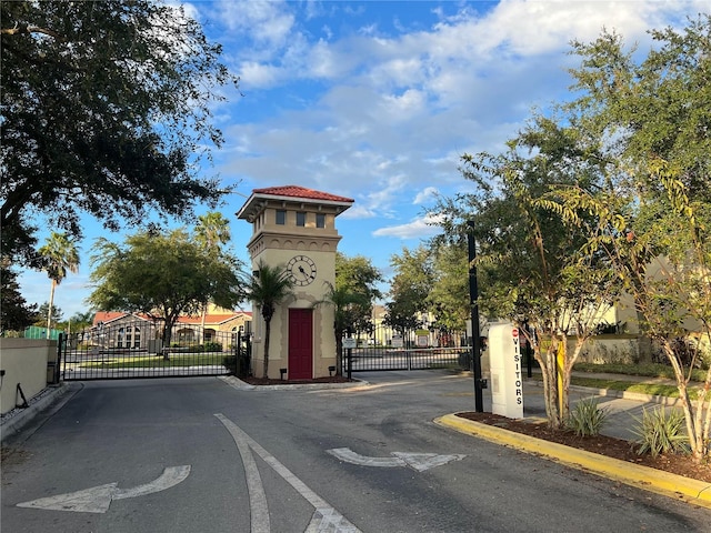 2770 Club Cortile Cir Unit A, Kissimmee, FL 34746 - view of asphalt road with a gate, curbs, a gated entry, and street lights