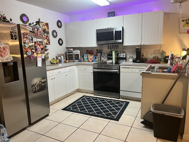 2770 Club Cortile Cir Unit A, Kissimmee, FL 34746 - kitchen featuring appliances with stainless steel finishes, white cabinetry, light tile patterned floors, and light countertops