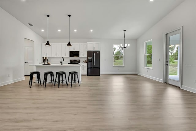 9739 Loretto St, Spring Hill, FL 34608 - kitchen with black appliances, a breakfast bar area, light wood-style flooring, white cabinets, and recessed lighting