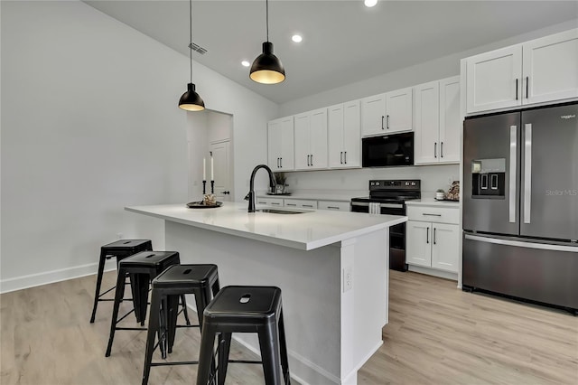 9739 Loretto St, Spring Hill, FL 34608 - kitchen with black appliances, light wood-style floors, white cabinetry, a kitchen island with sink, and a kitchen bar