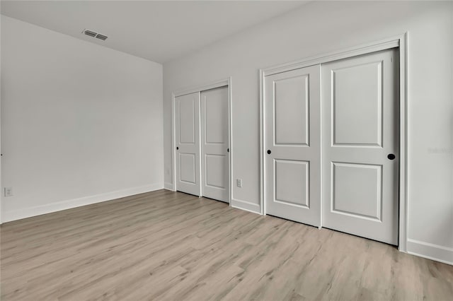 9739 Loretto St, Spring Hill, FL 34608 - unfurnished bedroom with multiple closets and light wood-style flooring