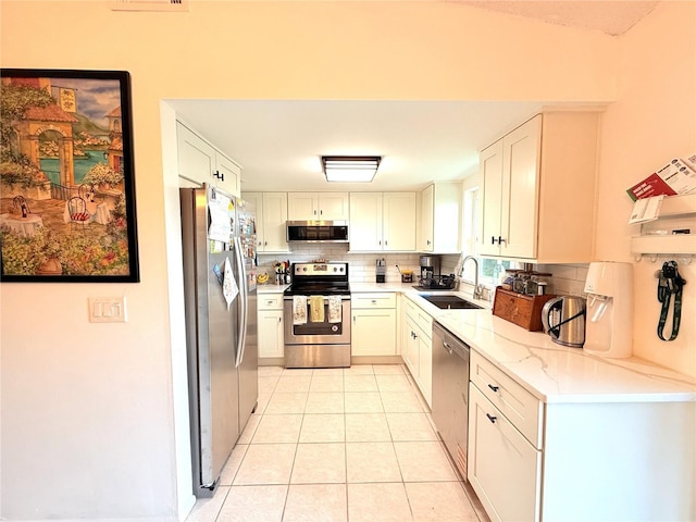 11310 Darlington Dr, Orlando, FL 32837 - kitchen with appliances with stainless steel finishes, decorative backsplash, light tile patterned flooring, light stone countertops, and white cabinetry
