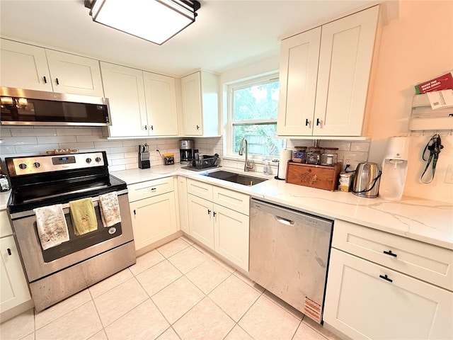 11310 Darlington Dr, Orlando, FL 32837 - kitchen featuring appliances with stainless steel finishes, tasteful backsplash, light tile patterned flooring, and white cabinets
