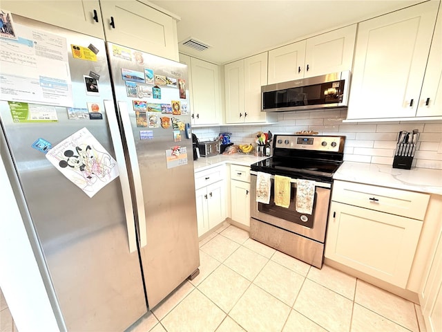 11310 Darlington Dr, Orlando, FL 32837 - kitchen with stainless steel appliances, light tile patterned floors, tasteful backsplash, light stone counters, and white cabinetry