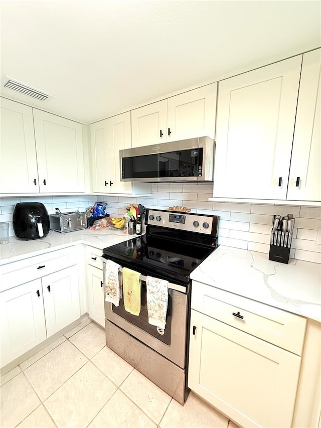 11310 Darlington Dr, Orlando, FL 32837 - kitchen featuring appliances with stainless steel finishes, tasteful backsplash, light tile patterned floors, light stone countertops, and white cabinetry