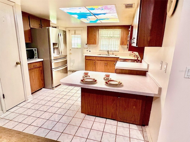 8547 Cedar Cove Dr, Orlando, FL 32819 - kitchen with appliances with stainless steel finishes, light countertops, a peninsula, light tile patterned floors, and brown cabinets