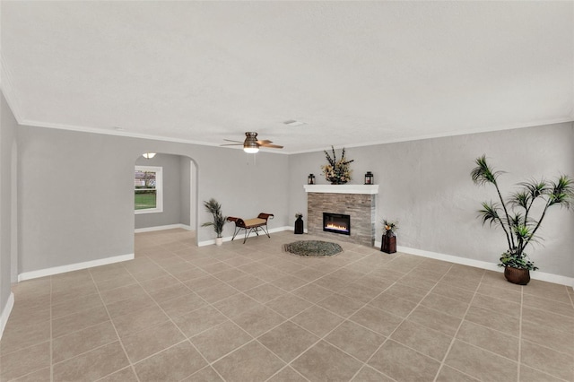 1506 S Elliott St, Sanford, FL 32771 - unfurnished living room featuring a ceiling fan, ornamental molding, arched walkways, light tile patterned floors, and a glass covered fireplace