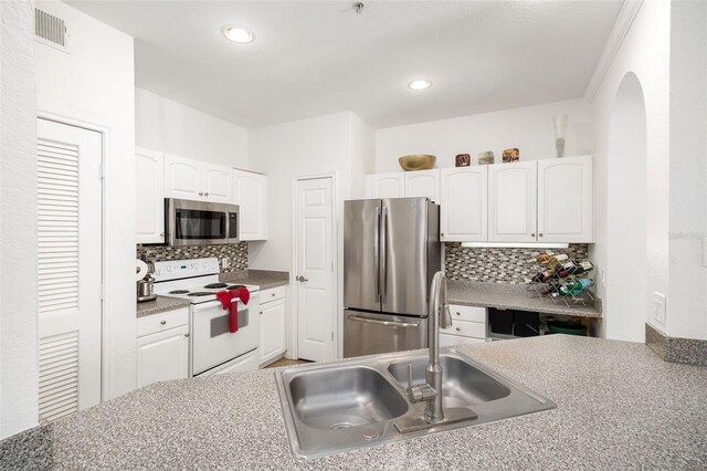 860 N Orange Ave Unit 210, Orlando, FL 32801 - kitchen with stainless steel appliances, white cabinets, backsplash, recessed lighting, and arched walkways