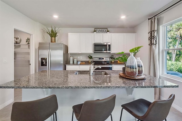 5157 Masser Rd, Saint Cloud, FL 34772 - kitchen with stainless steel appliances, white cabinetry, a kitchen breakfast bar, recessed lighting, and dark stone countertops