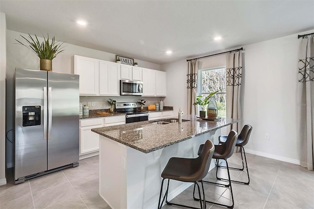 5157 Masser Rd, Saint Cloud, FL 34772 - kitchen featuring appliances with stainless steel finishes, white cabinetry, light tile patterned floors, dark stone countertops, and recessed lighting