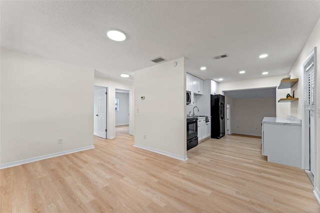 235 Ruth Blvd, Longwood, FL 32750 - kitchen with black appliances, light wood-style floors, white cabinets, light countertops, and recessed lighting