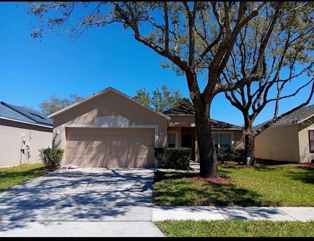 3530 Stonefield Dr, Orlando, FL 32826 - ranch-style house featuring a garage, stucco siding, driveway, and a front yard