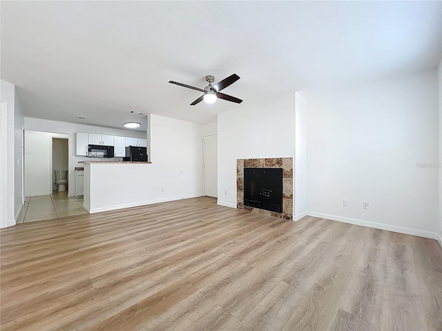 645 Stafford Ter Unit 163, Altamonte Springs, FL 32714 - unfurnished living room featuring a ceiling fan, light wood finished floors, and a tiled fireplace