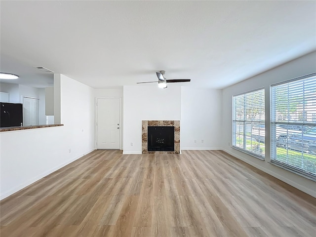 645 Stafford Ter Unit 163, Altamonte Springs, FL 32714 - unfurnished living room with light wood-type flooring, a tiled fireplace, and a ceiling fan