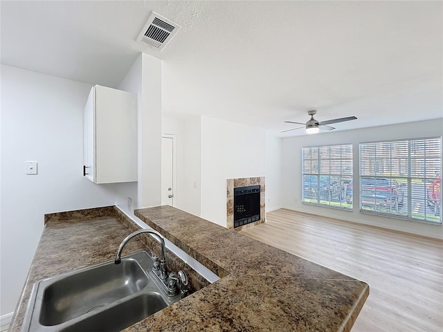 645 Stafford Ter Unit 163, Altamonte Springs, FL 32714 - kitchen with light wood-type flooring, a ceiling fan, white cabinets, a fireplace, and dark countertops