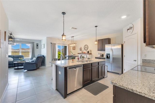 633 Greymount St, Davenport, FL 33837 - kitchen with appliances with stainless steel finishes, dark brown cabinets, pendant lighting, open floor plan, and light tile patterned floors