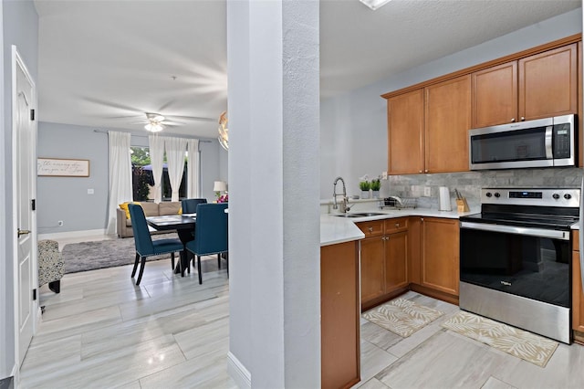 6027 Strada Isle Way, Orlando, FL 32835 - kitchen with stainless steel appliances, decorative backsplash, light countertops, and brown cabinetry