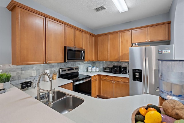 6027 Strada Isle Way, Orlando, FL 32835 - kitchen with appliances with stainless steel finishes, light countertops, decorative backsplash, brown cabinets, and a textured ceiling