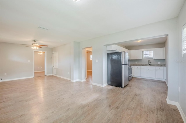 4559 W Gore Ave, Orlando, FL 32811 - kitchen featuring stainless steel appliances, white cabinetry, light wood finished floors, a ceiling fan, and open floor plan