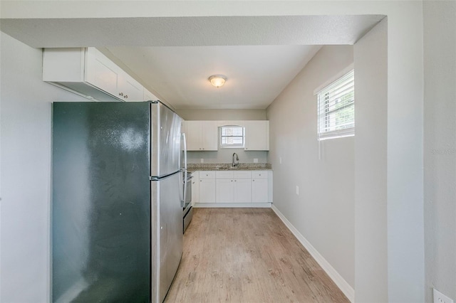 4559 W Gore Ave, Orlando, FL 32811 - kitchen with stainless steel appliances, light wood-style flooring, and white cabinets