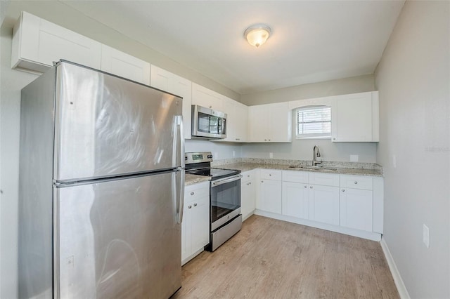 4559 W Gore Ave, Orlando, FL 32811 - kitchen featuring appliances with stainless steel finishes, light wood-type flooring, white cabinetry, and light stone counters