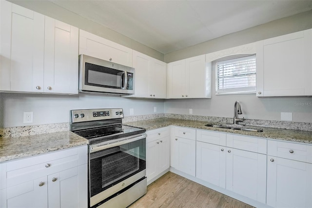 4559 W Gore Ave, Orlando, FL 32811 - kitchen featuring appliances with stainless steel finishes, white cabinetry, light wood-type flooring, and light stone counters