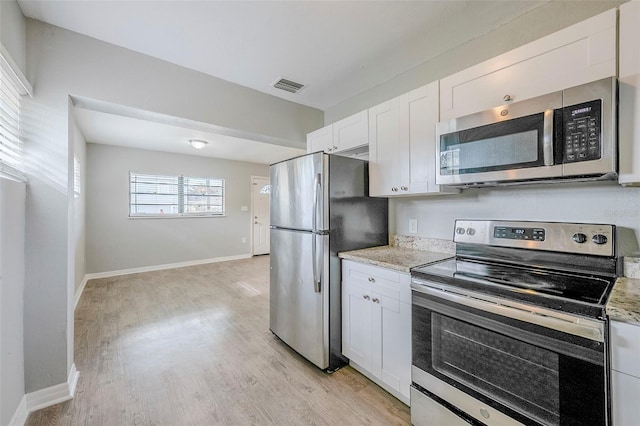 4559 W Gore Ave, Orlando, FL 32811 - kitchen featuring appliances with stainless steel finishes, white cabinetry, light wood-style floors, and light stone countertops