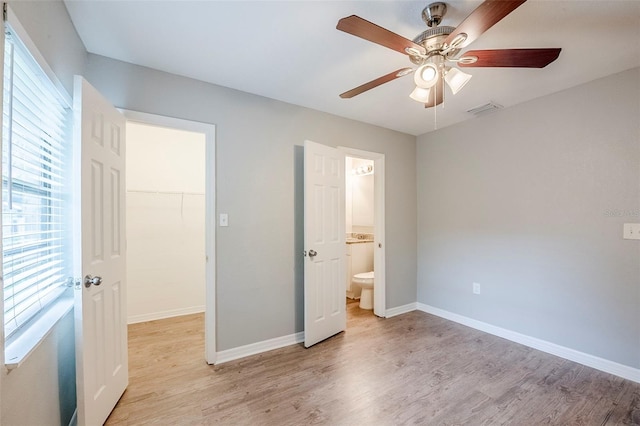 4559 W Gore Ave, Orlando, FL 32811 - unfurnished bedroom with a spacious closet, light wood-type flooring, a ceiling fan, and connected bathroom