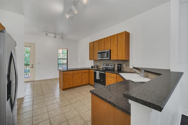 506 Mirasol Cir Unit 202, Celebration, FL 34747 - kitchen featuring appliances with stainless steel finishes, a peninsula, light tile patterned flooring, dark countertops, and backsplash