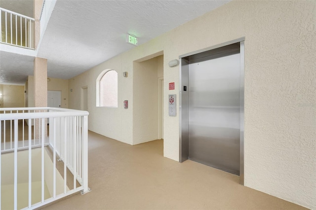 6336 Buford St Unit 209, Orlando, FL 32835 - hall featuring elevator, an upstairs landing, a textured wall, a textured ceiling, and finished concrete flooring