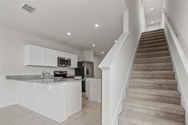 275 Blueberry Ln, Davenport, FL 33837 - kitchen featuring appliances with stainless steel finishes, a peninsula, light stone countertops, light tile patterned flooring, and recessed lighting